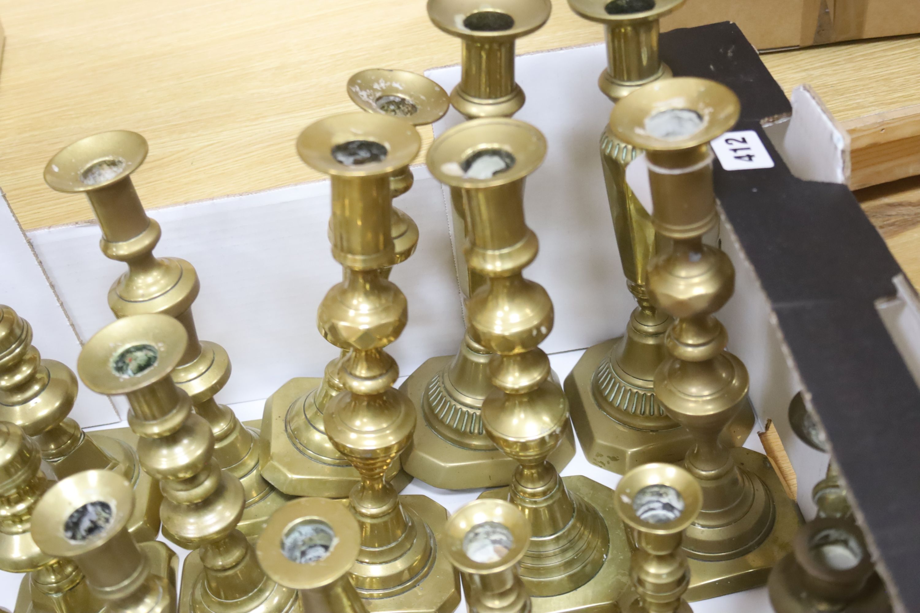 A large canteen of various brass candlesticks, mostly 19th century